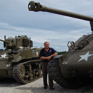 Judge Jim Osborne standing with some WWII tanks.