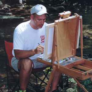 Photo of Judge Cox sitting outdoors at his easel