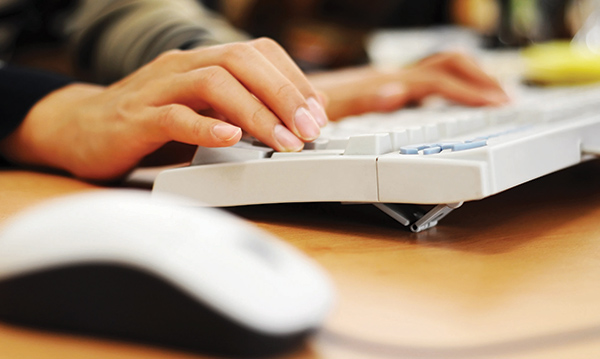 A woman types using a computer keyboard