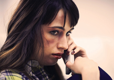 A battered woman holds a phone