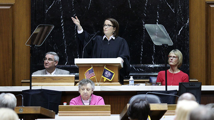 Chief Justice Loretta Rush gestures during the State of the Judiciary. Governor Holcomb and Lt. Gov. Crouch sit nearby.