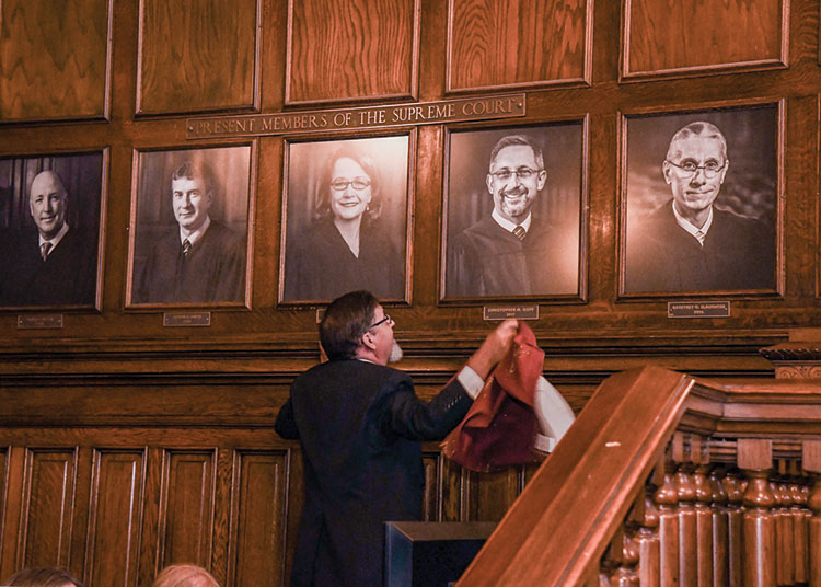 The curtain covering Justice Goff's formal portrait is removed during his investiture ceremony.