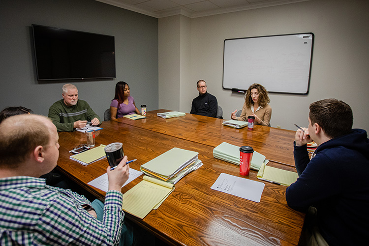 A group of people gather around a large conference table.