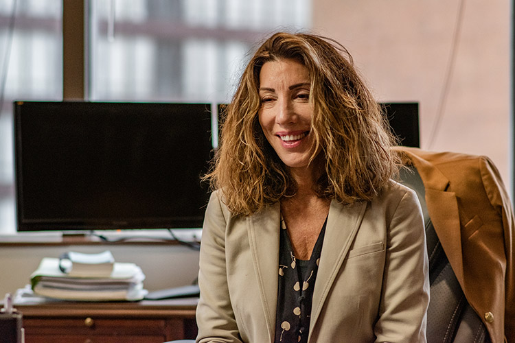 State Public Defender Amy Karozos sits at her desk, smiling.