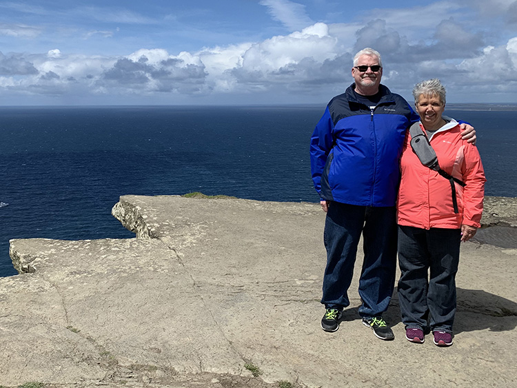 Judge Kimberly Dowling and her husband pose for a photo with the ocean behind them.