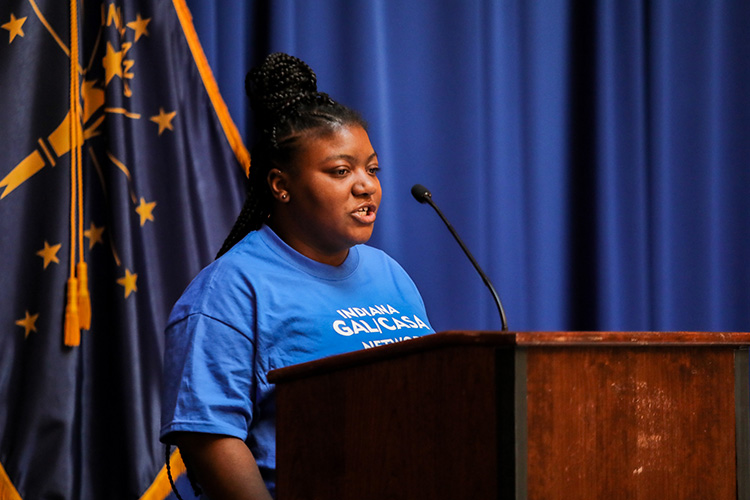 Former foster youth De’Coriyanna Garrett stands behind a podium at the Indiana State House during CASA Day.