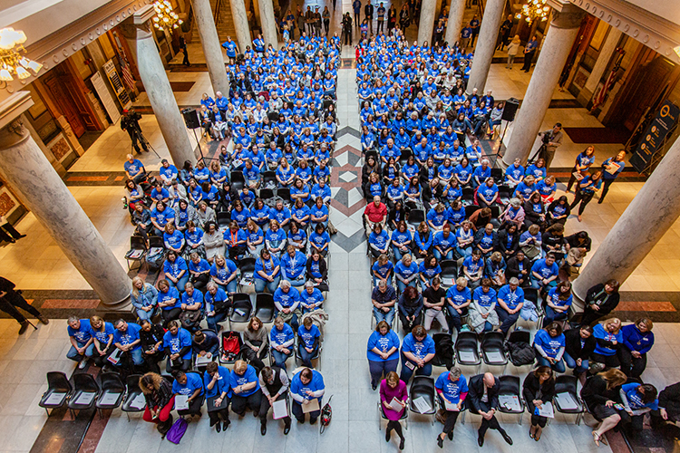 An overhead view of hundreds of CASA volunteers wearing blue shirts in the Indiana State House.