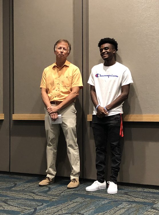 David Peppler and Erson stand together for a photo against a wall.