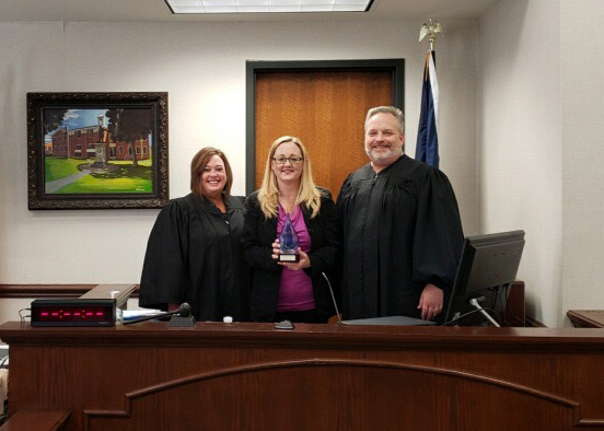 Kelly Shelhamer stands between Judges Marsha Howser and Judge Jason Mount in a Scott County courtroom.