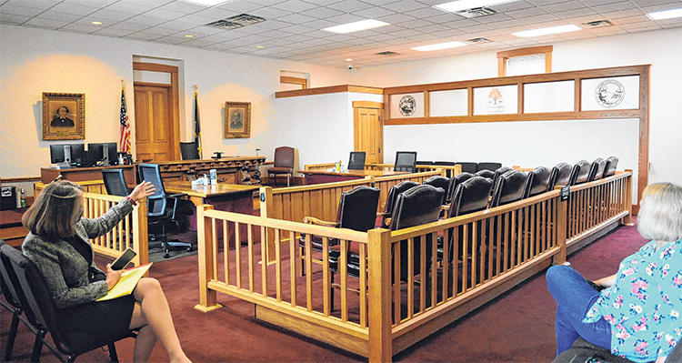 Two people sit socially distanced in a courtroom.