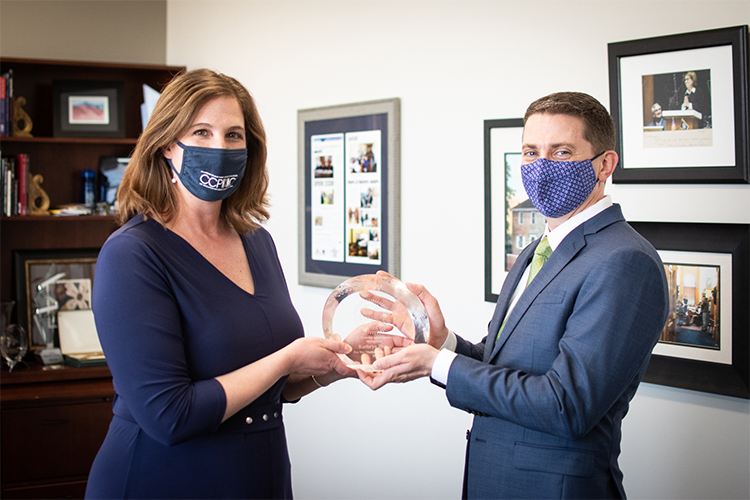 Kathryn Dolan and Justin Forkner wear masks in a well-lit office.