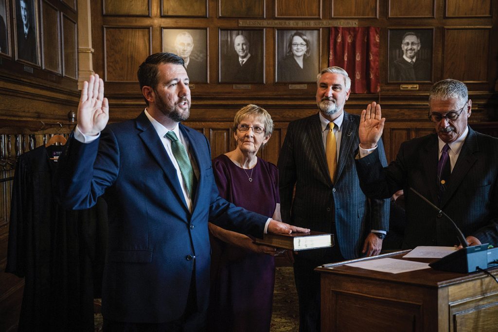 Newton Circuit Judge Daniel Molter administers the oath of office to his son, Hon. Derek Molter, with mother, Kate Molter, holding the bible, and Gov. Eric Holcomb standing in participation after passing his duties to swear in the new justice to his proud father.