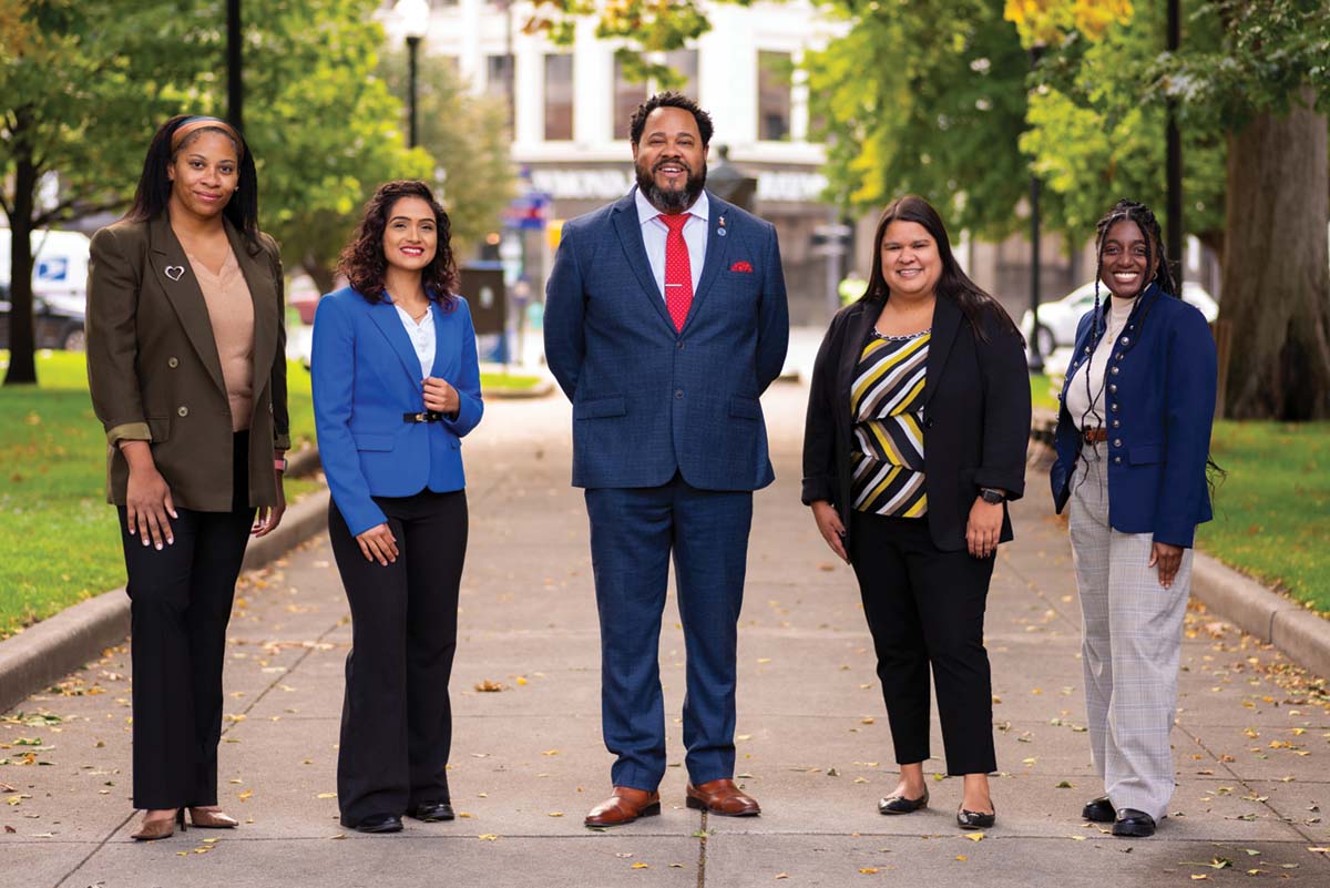 The five professionals who staff the Office of Diversity, Equity & Inclusion stand for a photo amid the turning leaves in a downtown Indianapolis park.