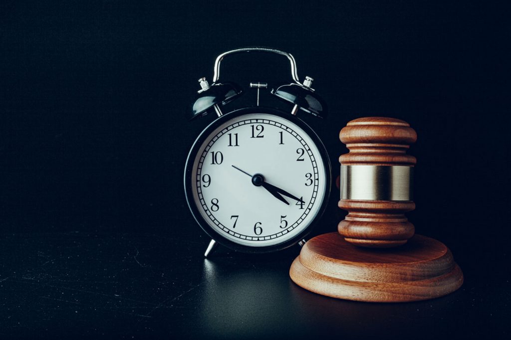 A judge's gavel sits on a table next to a clock.