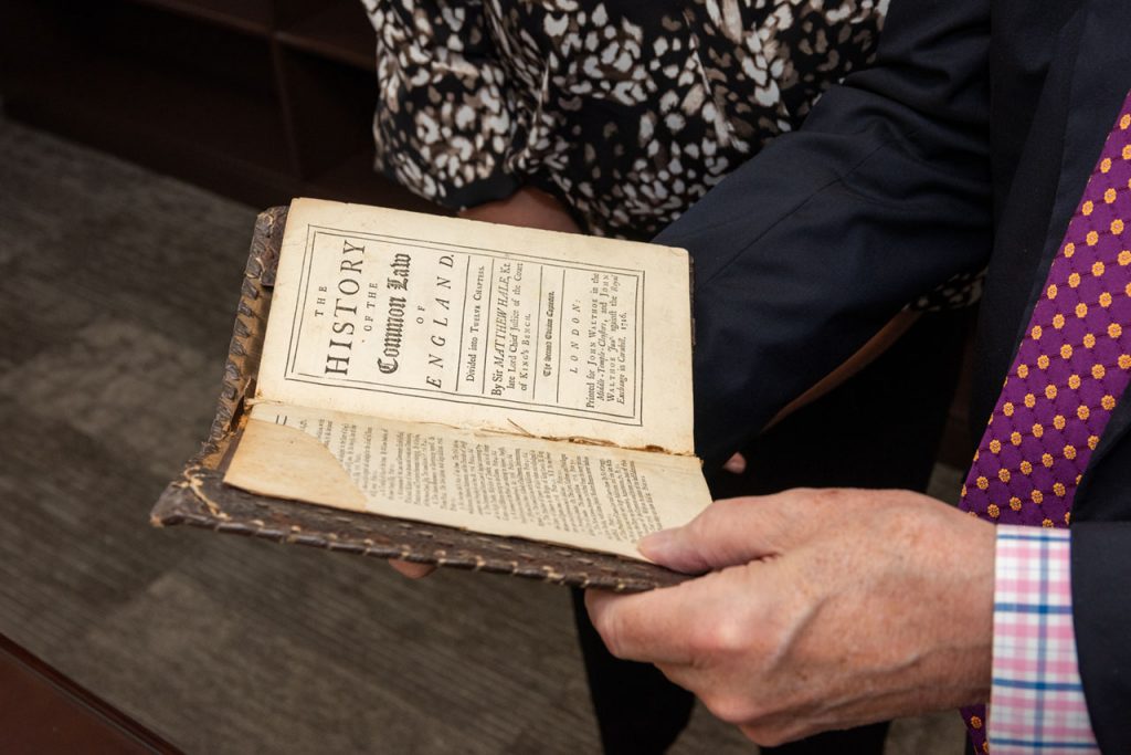 Former Chief Justice Randall Shepard shows one of the books from his donated collection to library staff.