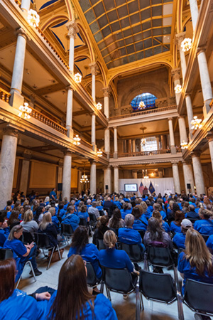Volunteers wearing blue shits fill the Statehouse atrium to hear from various speakers on CASA day.