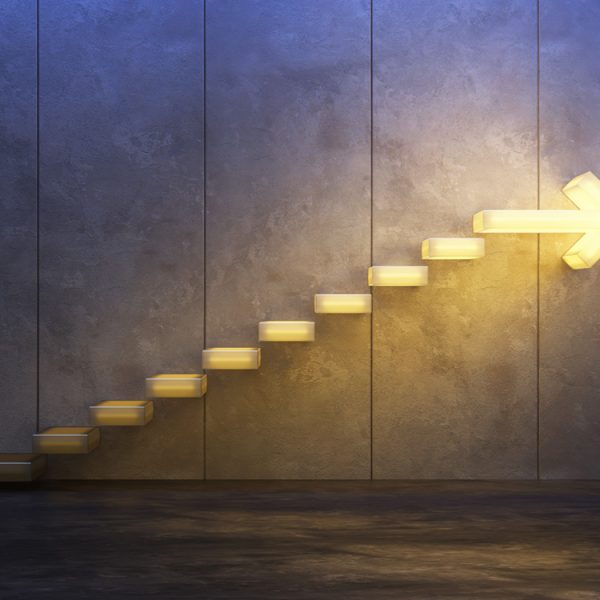 Lighted steps on a wall getting brighter as they lead toward an arrow pointing to the future.