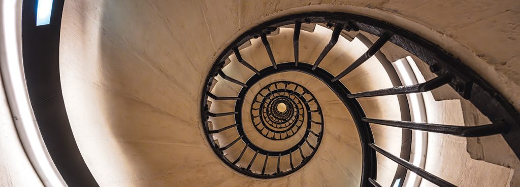 The guardrails of a spiral staircase from the bottom, looking upward through the center, illustrating the golden ratio.