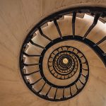 The guardrails of a spiral staircase from the bottom, looking upward through the center, illustrating the golden ratio.