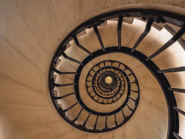 The guardrails of a spiral staircase from the bottom, looking upward through the center, illustrating the golden ratio.