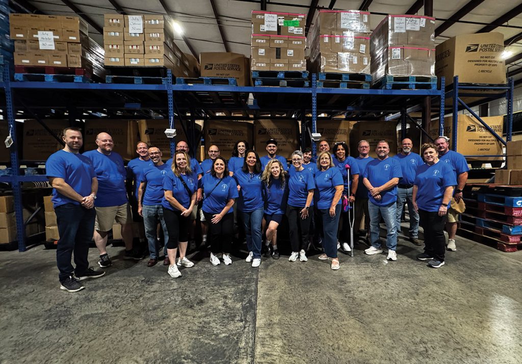 Group of people standing for a photo in a warehouse.