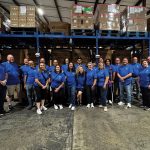 Group of people standing for a photo in a warehouse.