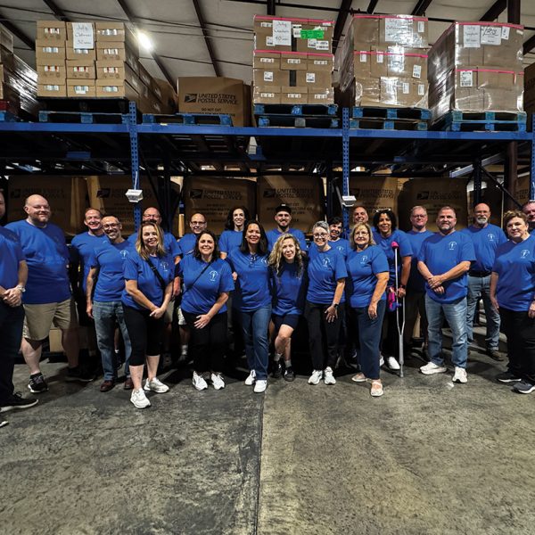 Group of people standing for a photo in a warehouse.