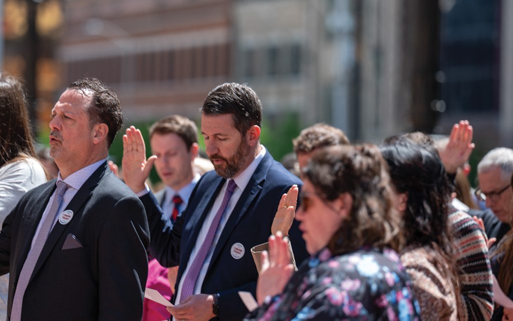 Group of people with right hand raised taking oath.