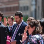 Group of people with right hand raised taking oath.
